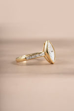 Gold bezel marquise ring with baguette band by Sami Jewels, showcasing a sleek design with marquise gemstone and baguette accents.