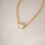 Detailed shot of Bezel Set Emerald Cut Necklace, highlighting the smooth, tactile edges of the gold setting.