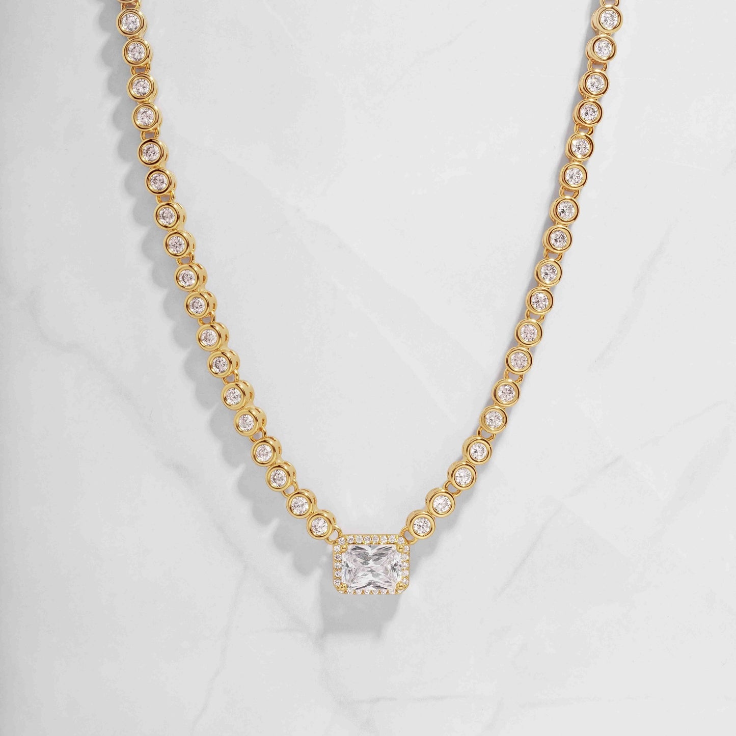 Gold diamond baguette tennis necklace for women, with tiny round bezel settings on white background