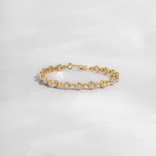 Gold tennis bracelet with bead and bezel accents.