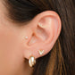 model wearing gold jewelry featuring a gold hoop earring and a tiny bee stud earring 