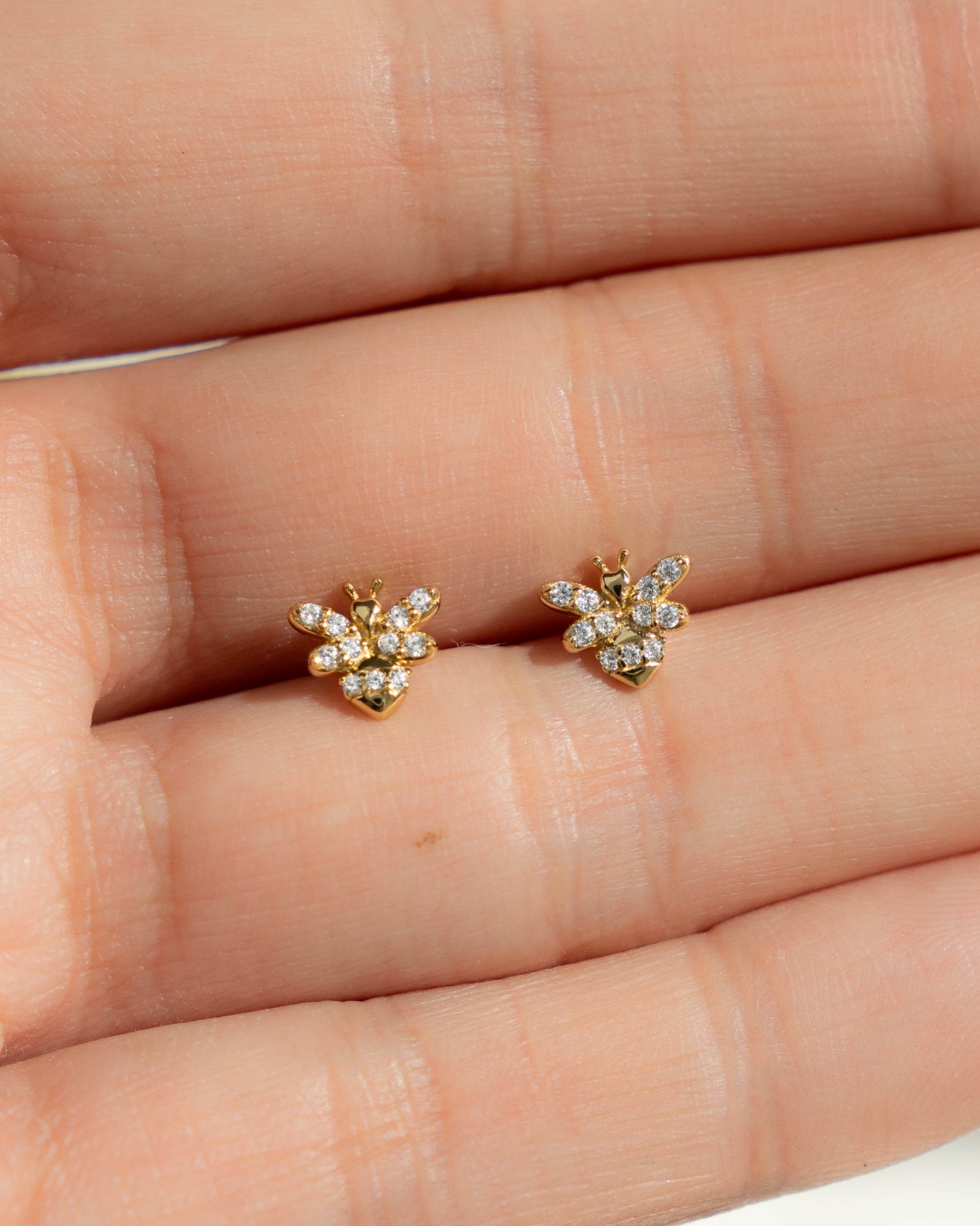 models hand showcasing dainty bee stud earring with dainty cubic zirconia stones