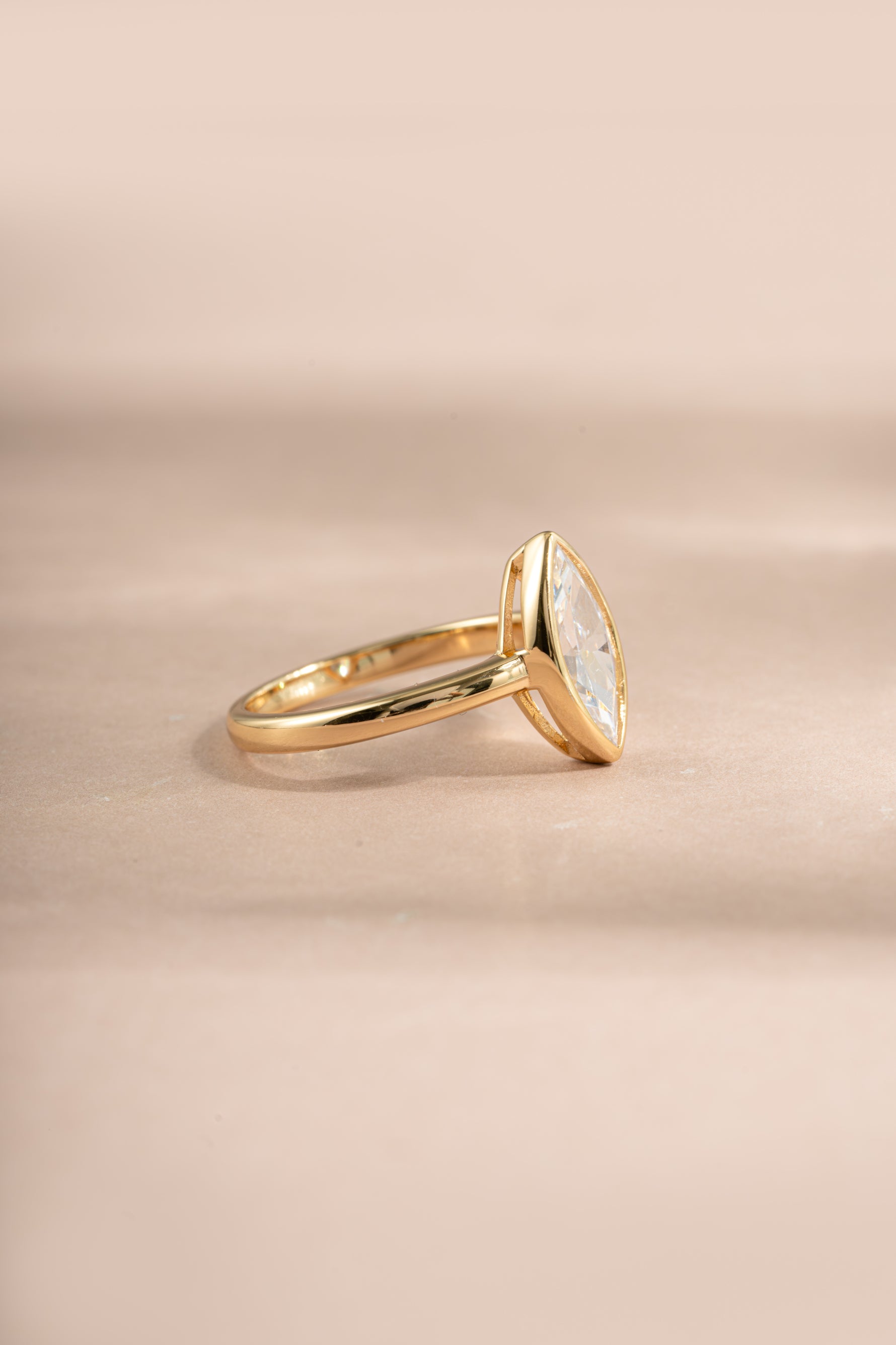 Gold bezel marquise ring by Sami Jewels shown from a side view, highlighting its elegant design and detailed craftsmanship.