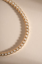 Gold bezel square tennis necklace by Sami Jewels, layered with cubic zirconia accents, elegant jewelry for everyday wear.