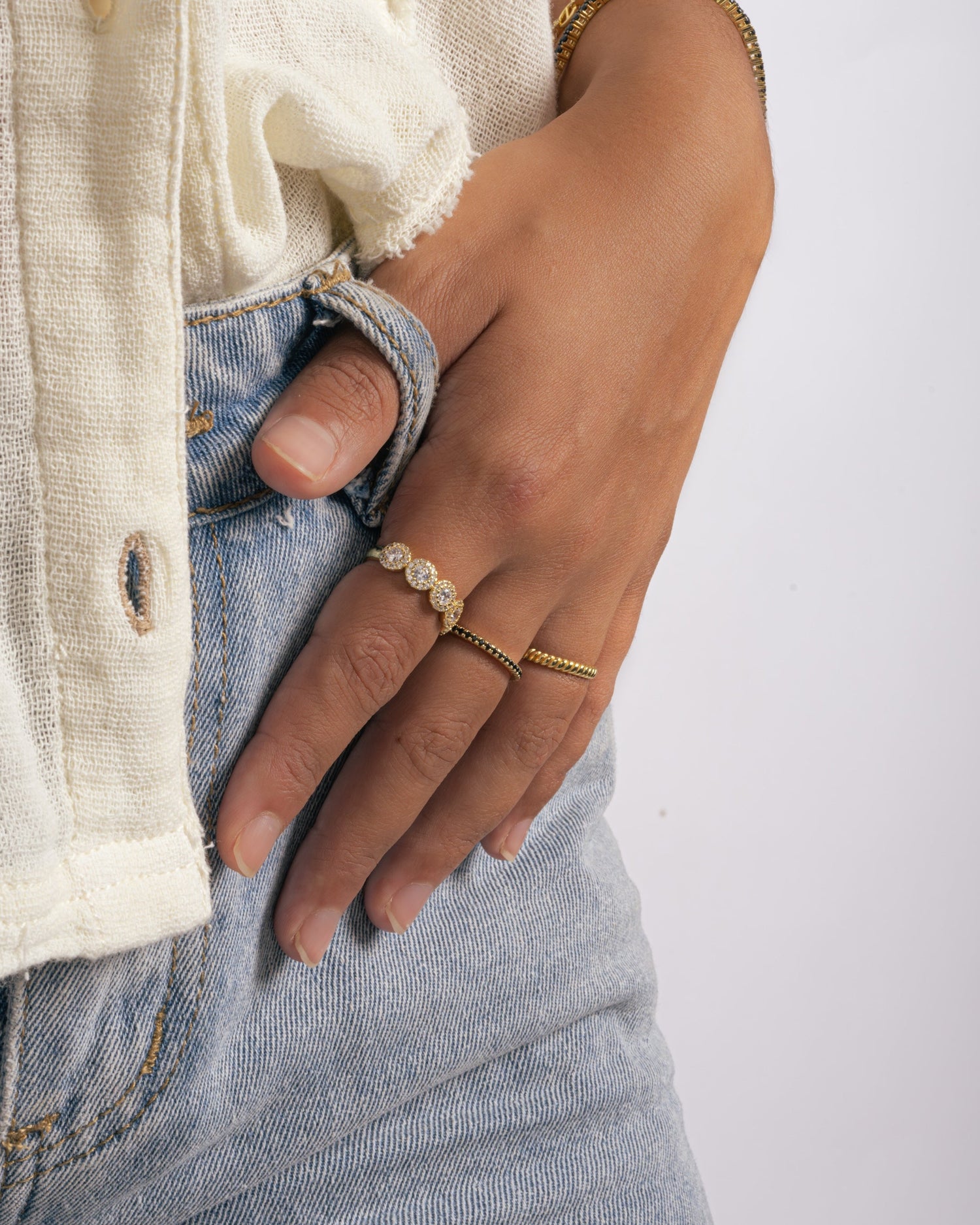 gold black diamond eternity ring with gold stackable rings on womens hand