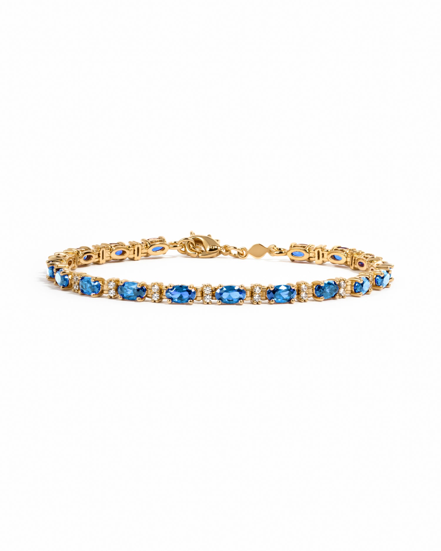 A gold tennis bracelet featuring a row of oval-cut blue gemstones with alternating white round stones.