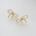 close up of shimmering cubic zirconia earrings with a bow design, highlighting its intricate diamond details. 