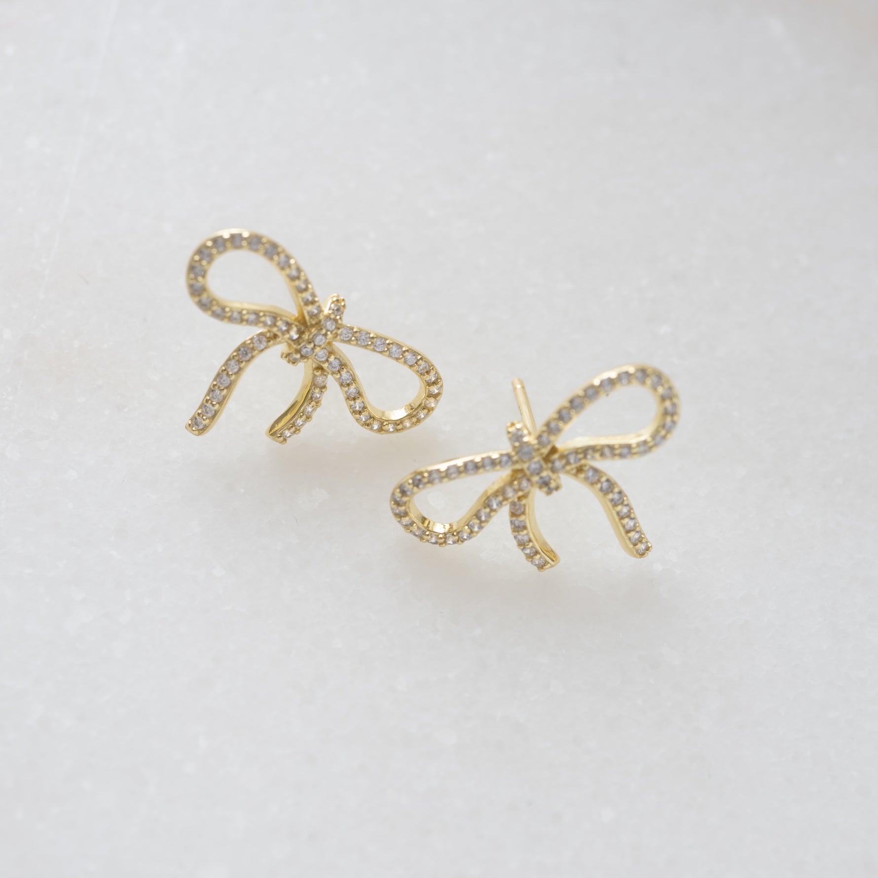 close up of shimmering cubic zirconia earrings with a bow design, highlighting its intricate diamond details. 