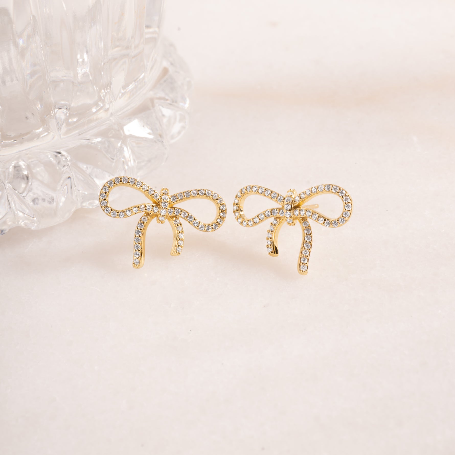 flat lay of gold earrings, highlighting its refined bow design