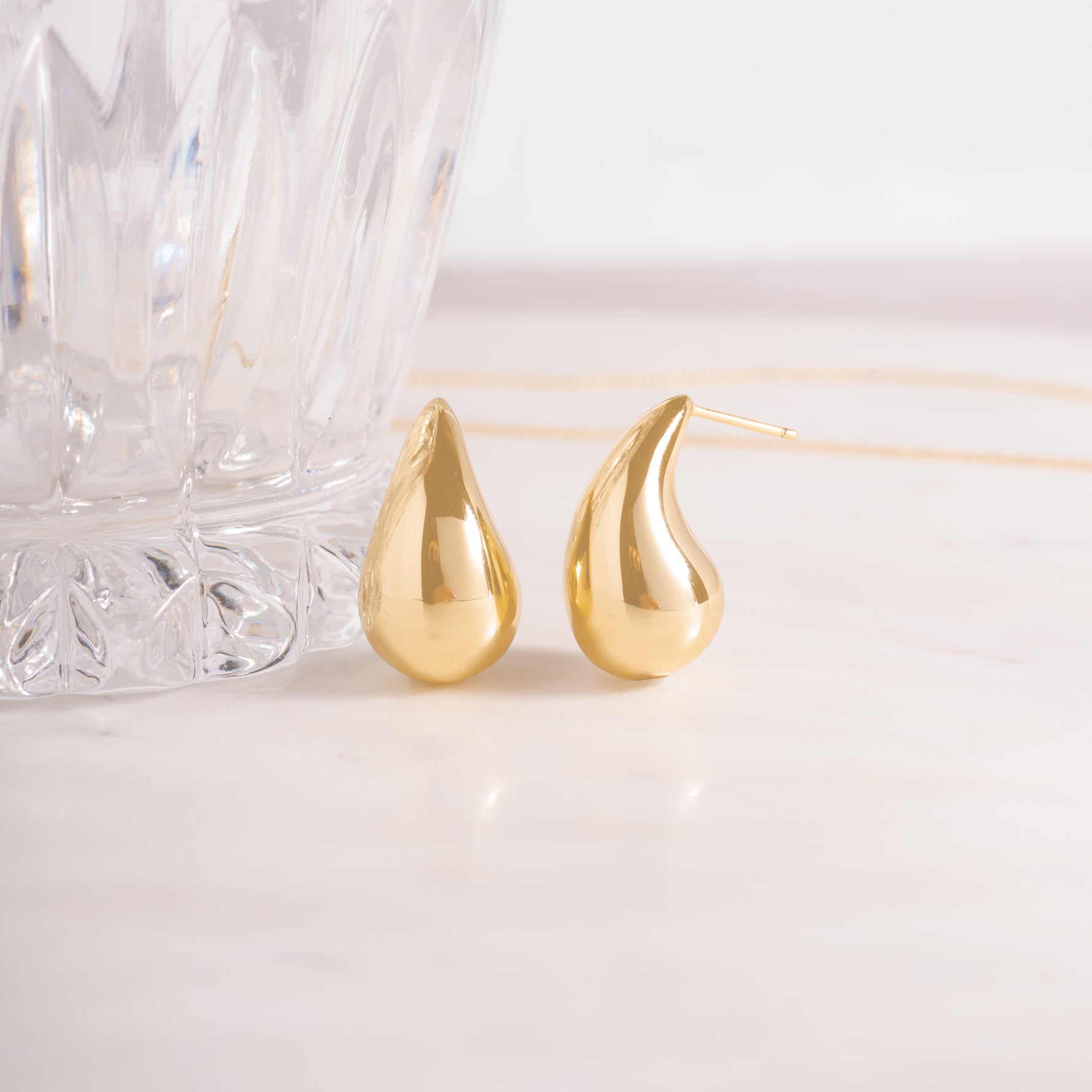 close up of statement drop earrings, featuring a thick, rounded teardrop. 