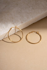 gold classic hoop earrings in 30mm size neutral background