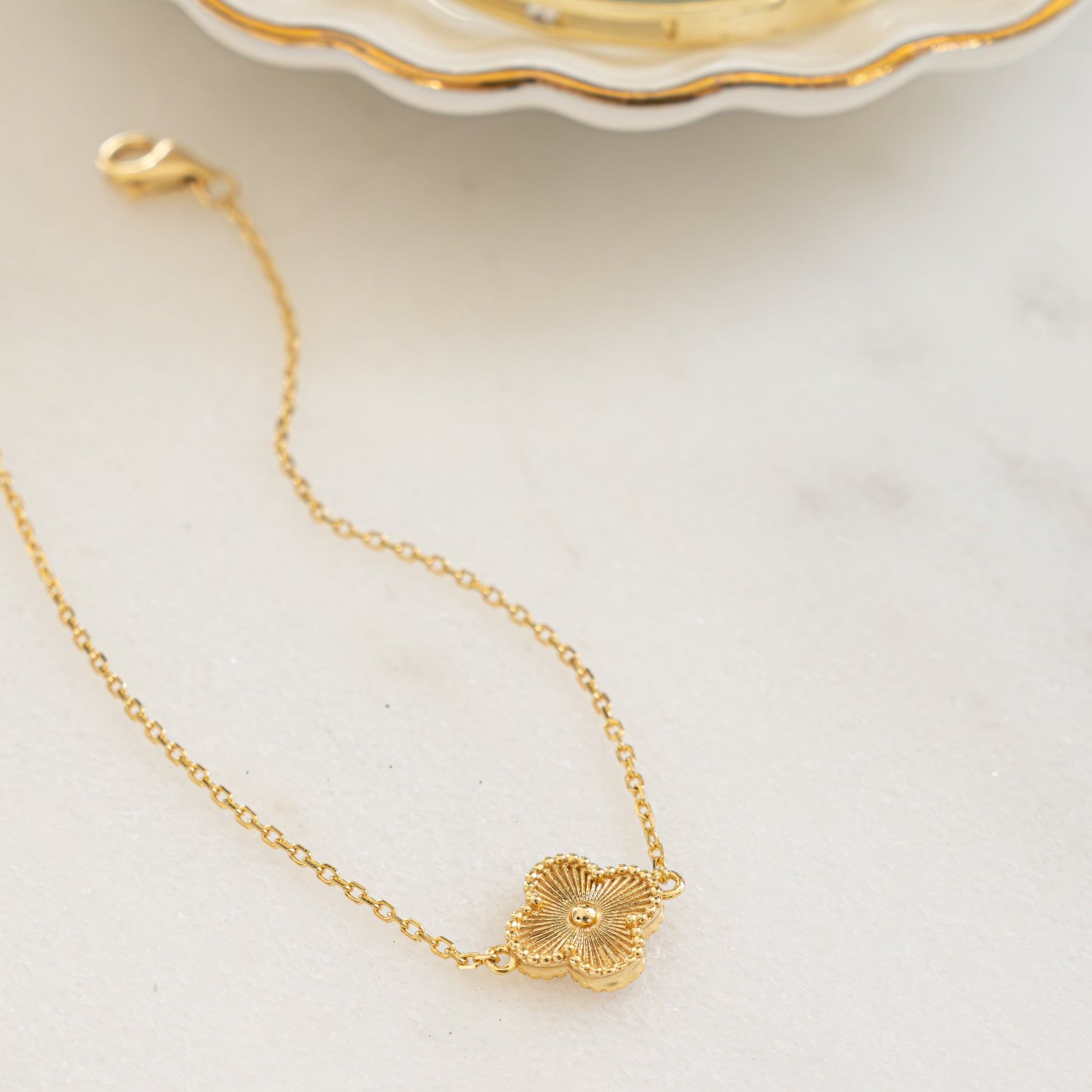 Flat lay of a single charm gold clover bracelet.