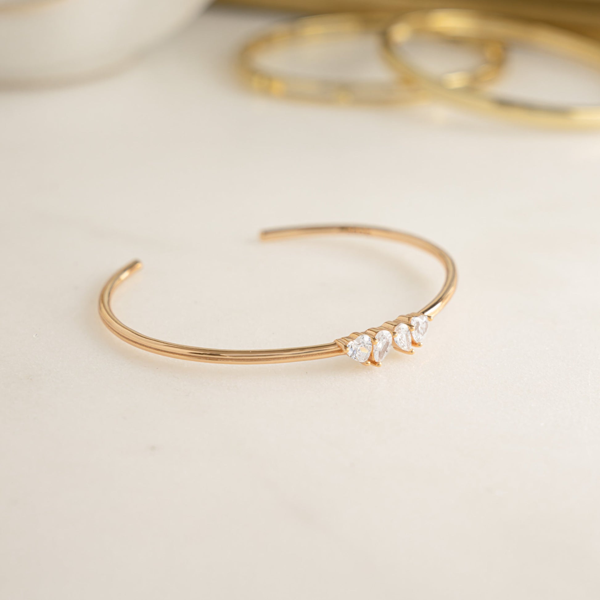 Side profile of a Toi et Moi gold bangle, adorned with teardrop and heart diamonds. 