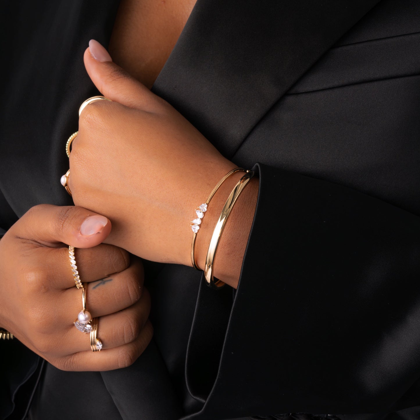 Model wearing Toi et Moi cuff bracelet in gold, worn alongside other gold bracelets, including gold bangles , for a layered, stylish look. Paired with dainty gold rings with diamond gemstones.