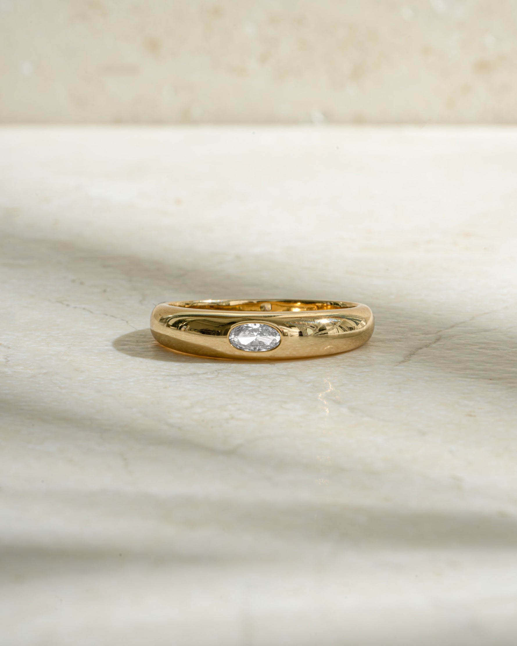 gold bezeled dome ring with cubic zirconia stone on neutral background