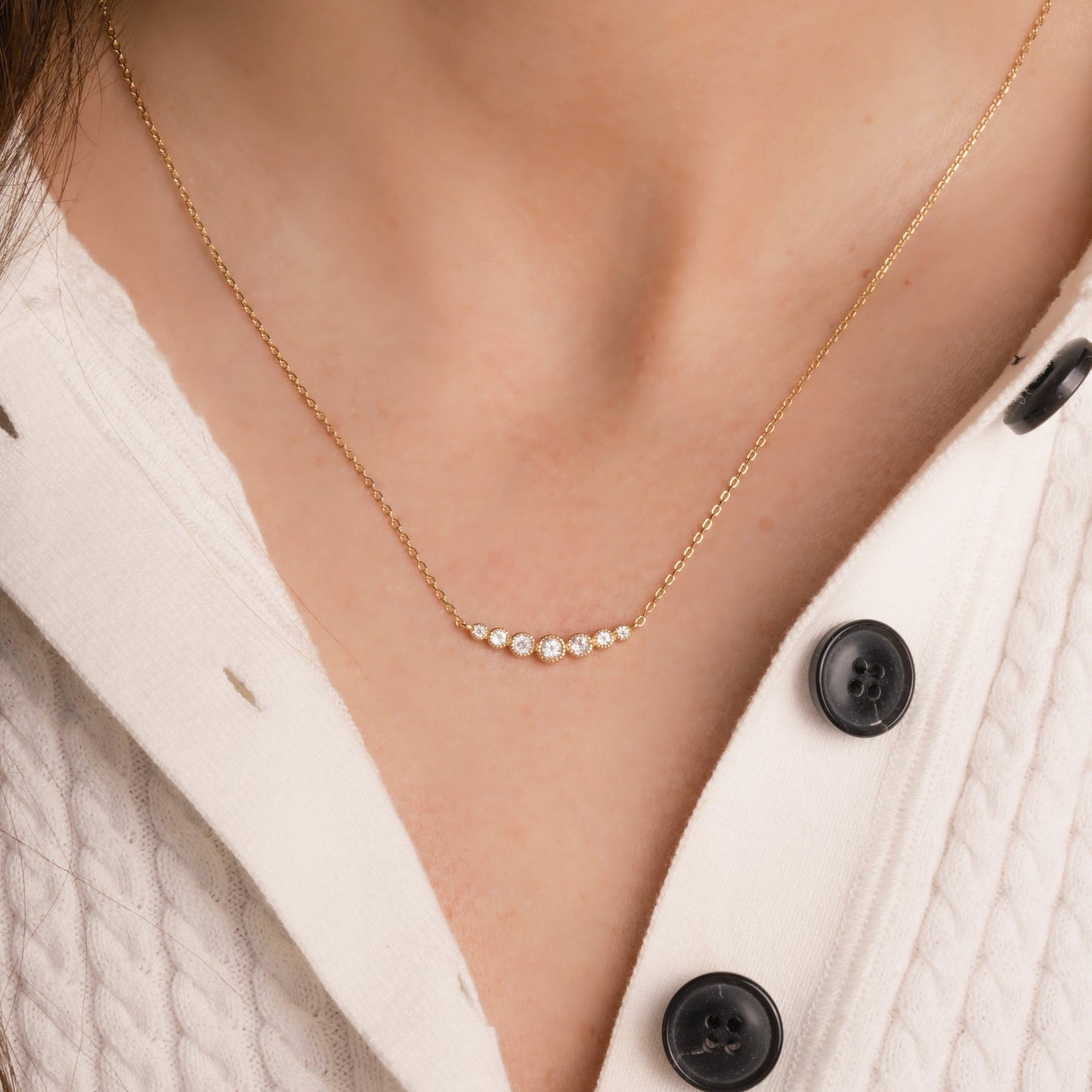 Gold diamond bezel necklace in gold worn on model wearing white sweater