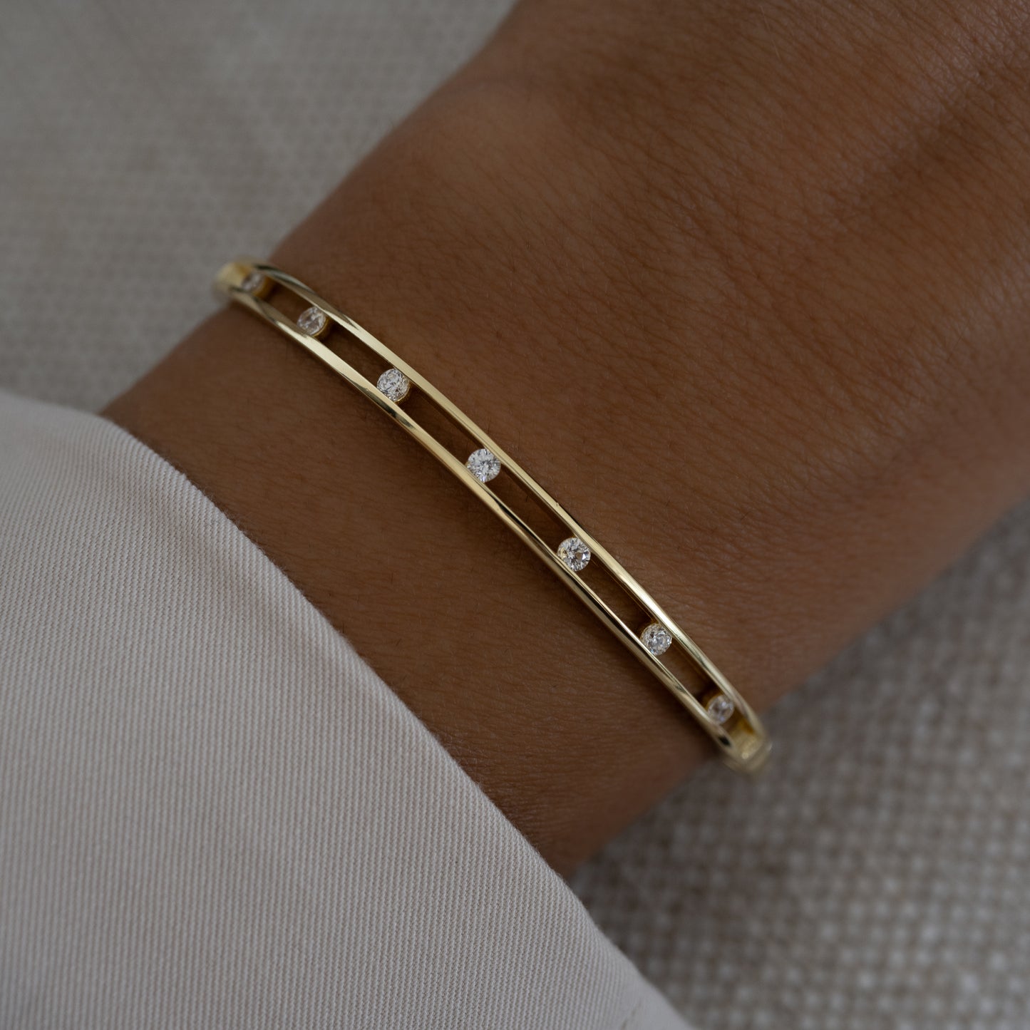 gold bangle bracelet with diamonds on a hand model