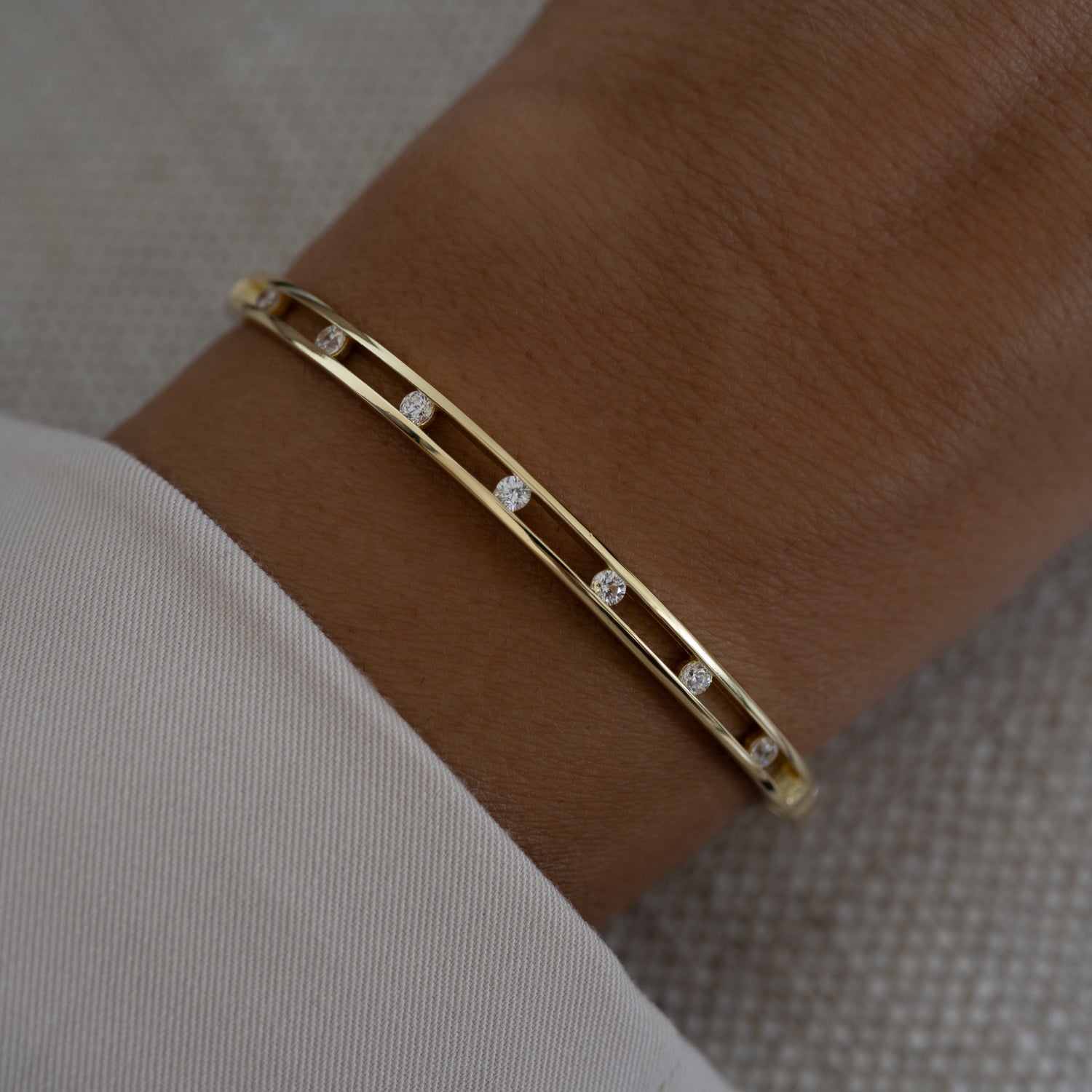 gold bangle bracelet with diamonds on a hand model