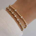 Gold  tennis bracelets with beads and diamond bezels.
