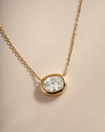 Close-up of the gold oval CZ pendant showing its horizontal bezel setting.