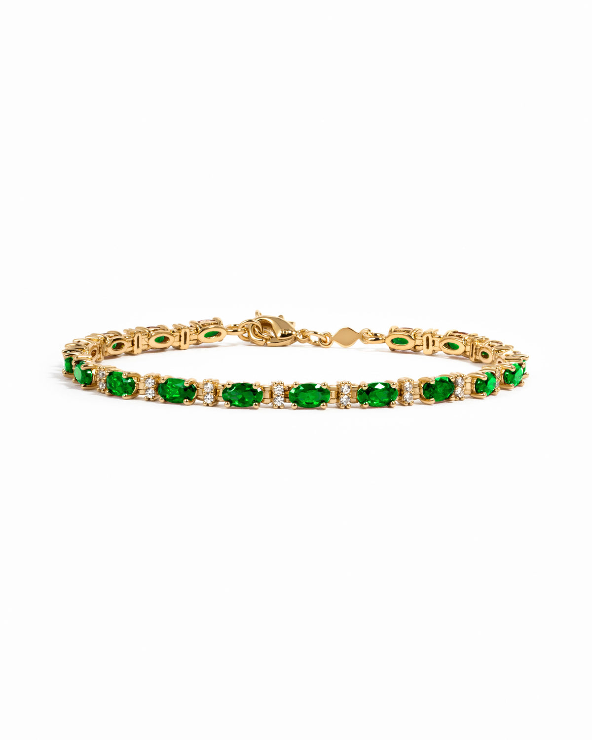 A gold tennis bracelet featuring a row of oval-cut green gemstones with alternating small clear stones.