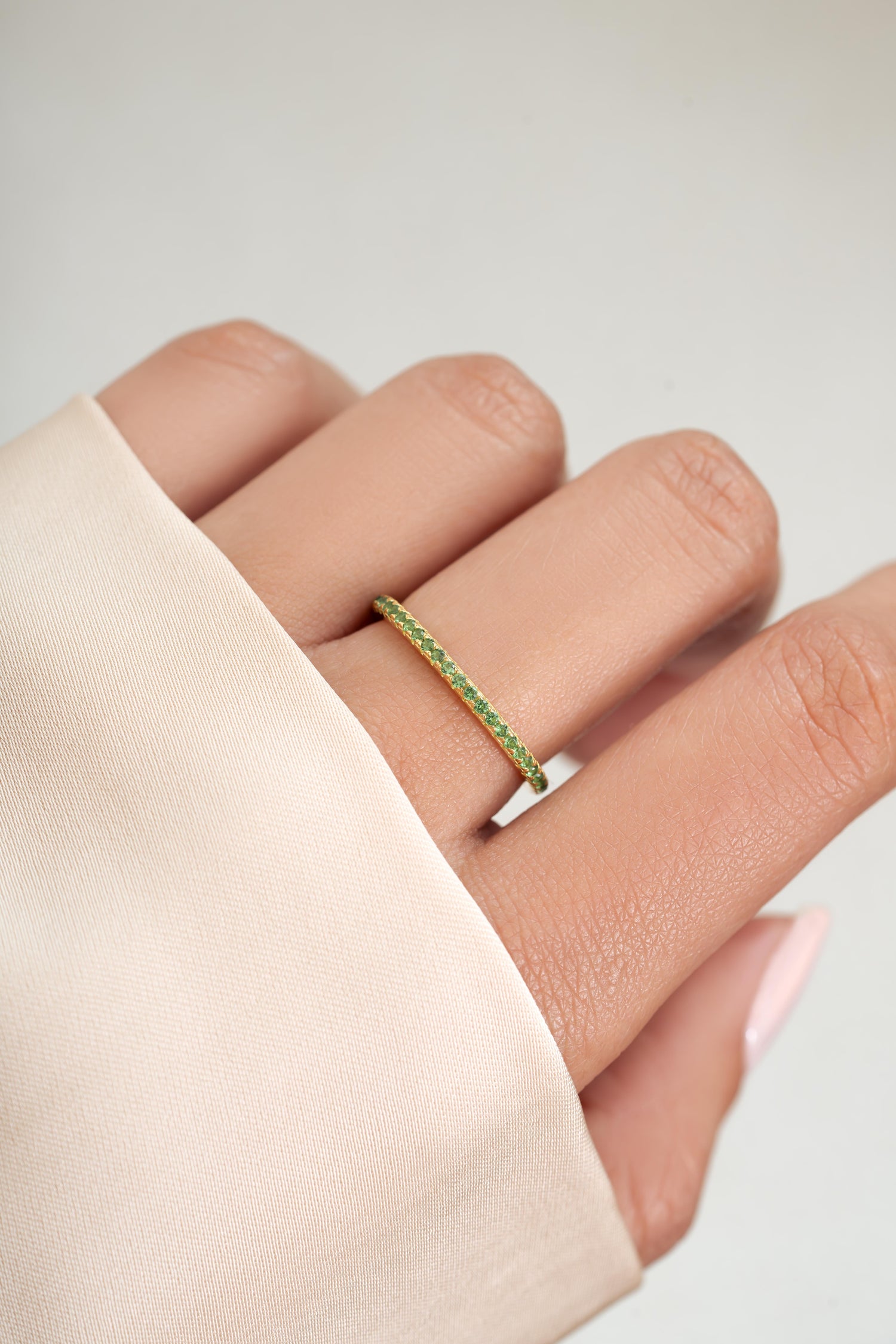 gold emerald birthstone eternity ring on womens hand 