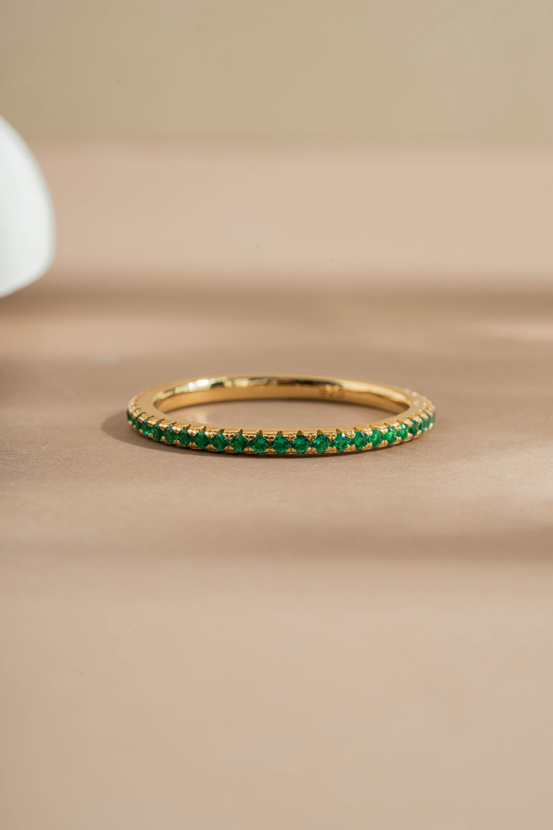gold emerald birthstone eternity ring neutral background