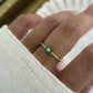 a model wearing a dainty emerald flower ring made of cz and emerald