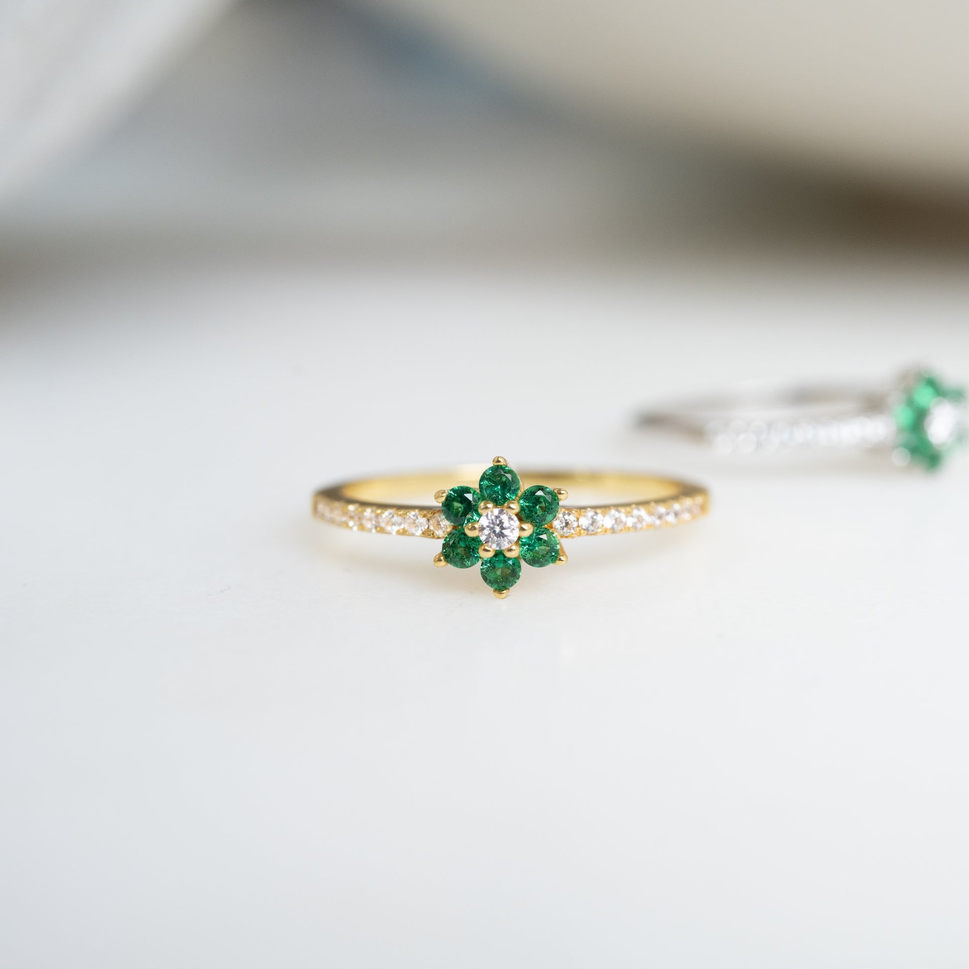 a minimalist gold emerald ring with a flower 