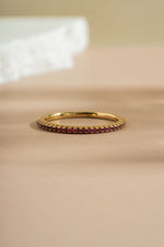 gold ruby birthstone eternity ring neutral background