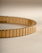 Close-up of the gold bangle's ribbed outer surface and smooth inner edge.