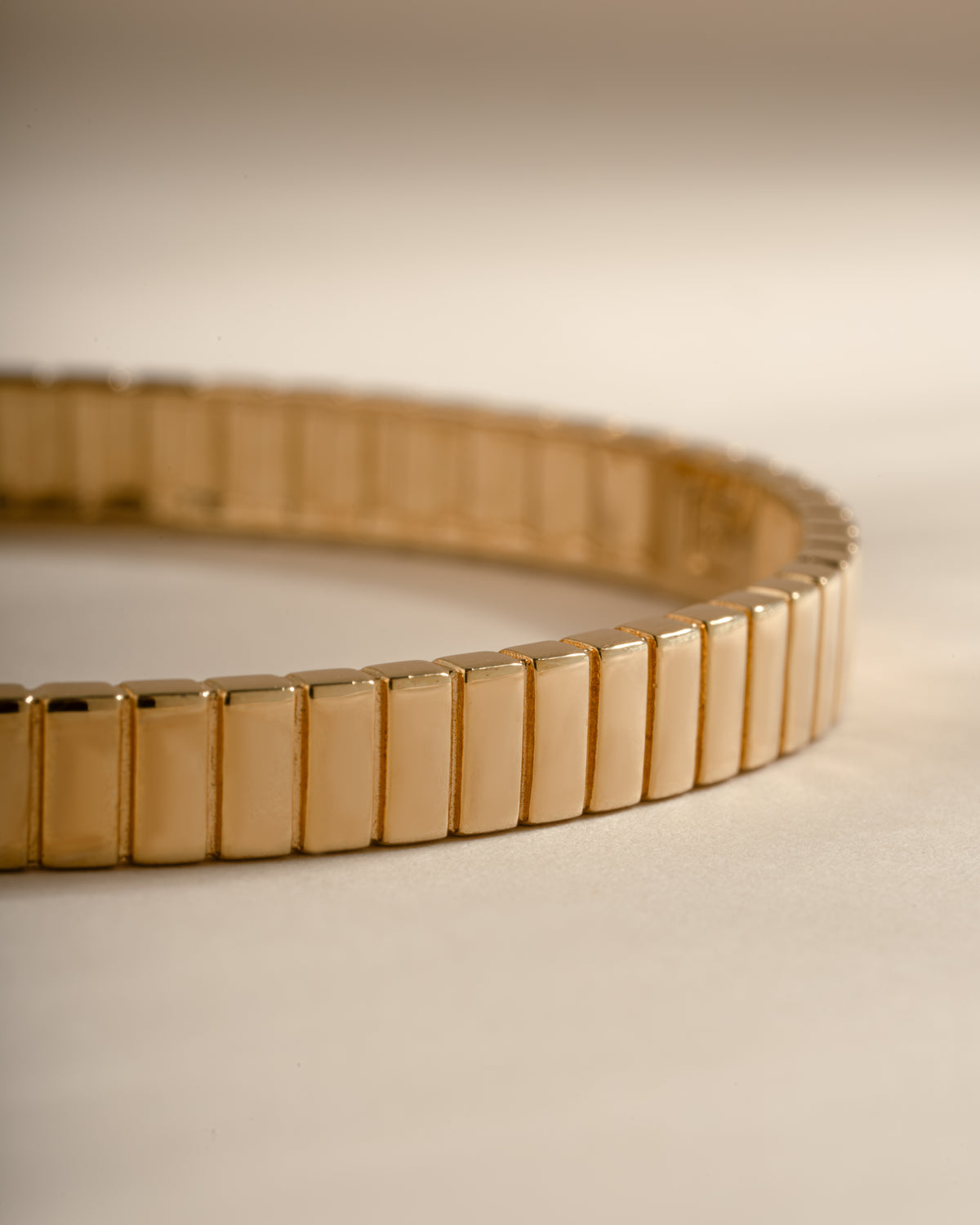 Close-up of the gold bangle's ribbed outer surface and smooth inner edge.