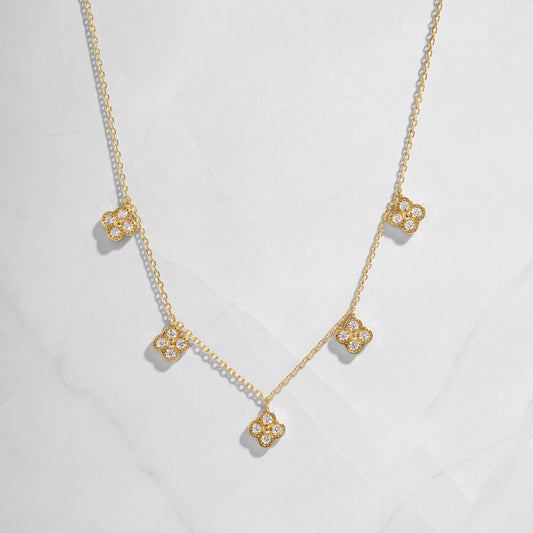 flat lay of a van cleef inspired charm necklace consisting of 5 small diamond four leaf clover charms