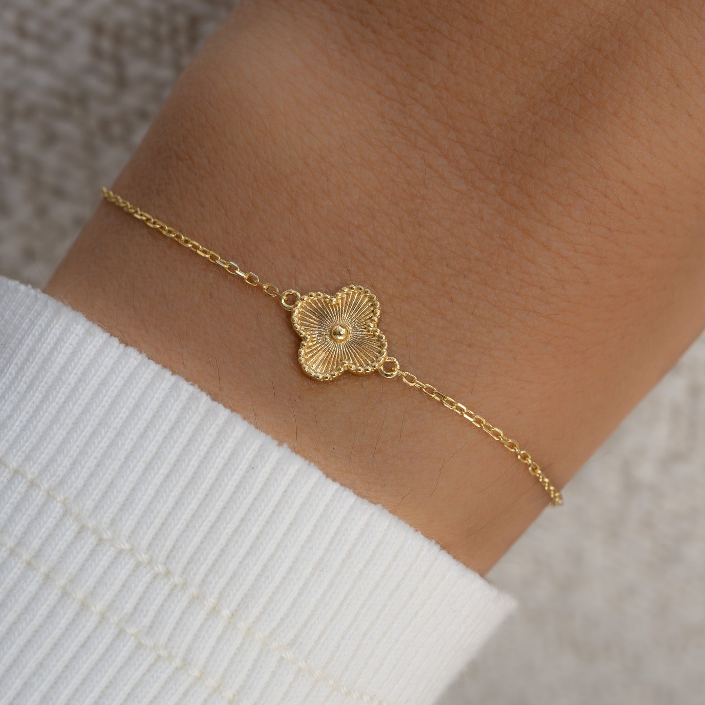 Model wearing a single charm four leaf clover bracelet in gold inspired by van cleef