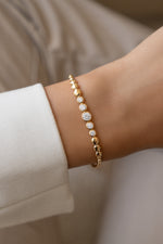 Gold graduated bezel tennis bracelet worn alone on a model's wrist.