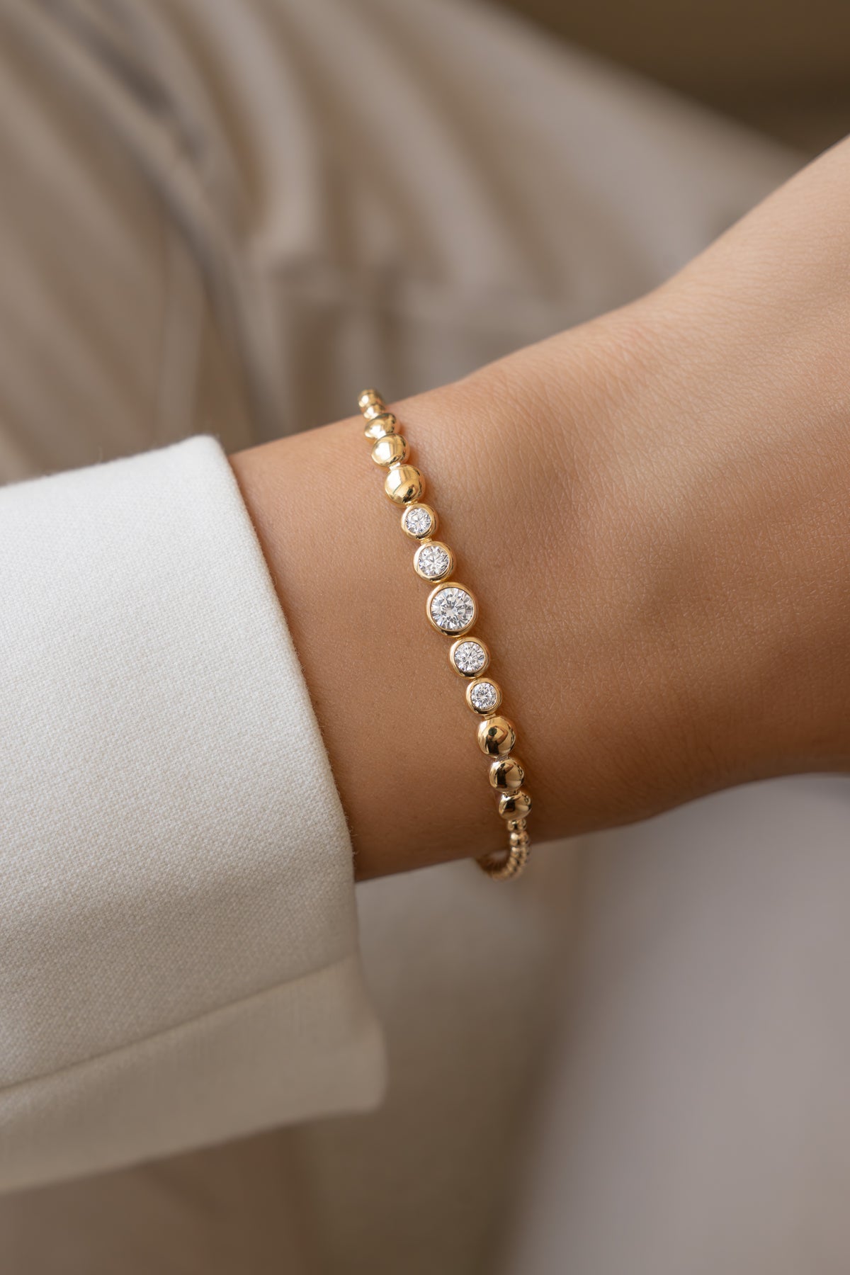 Gold graduated bezel tennis bracelet worn alone on a model's wrist.