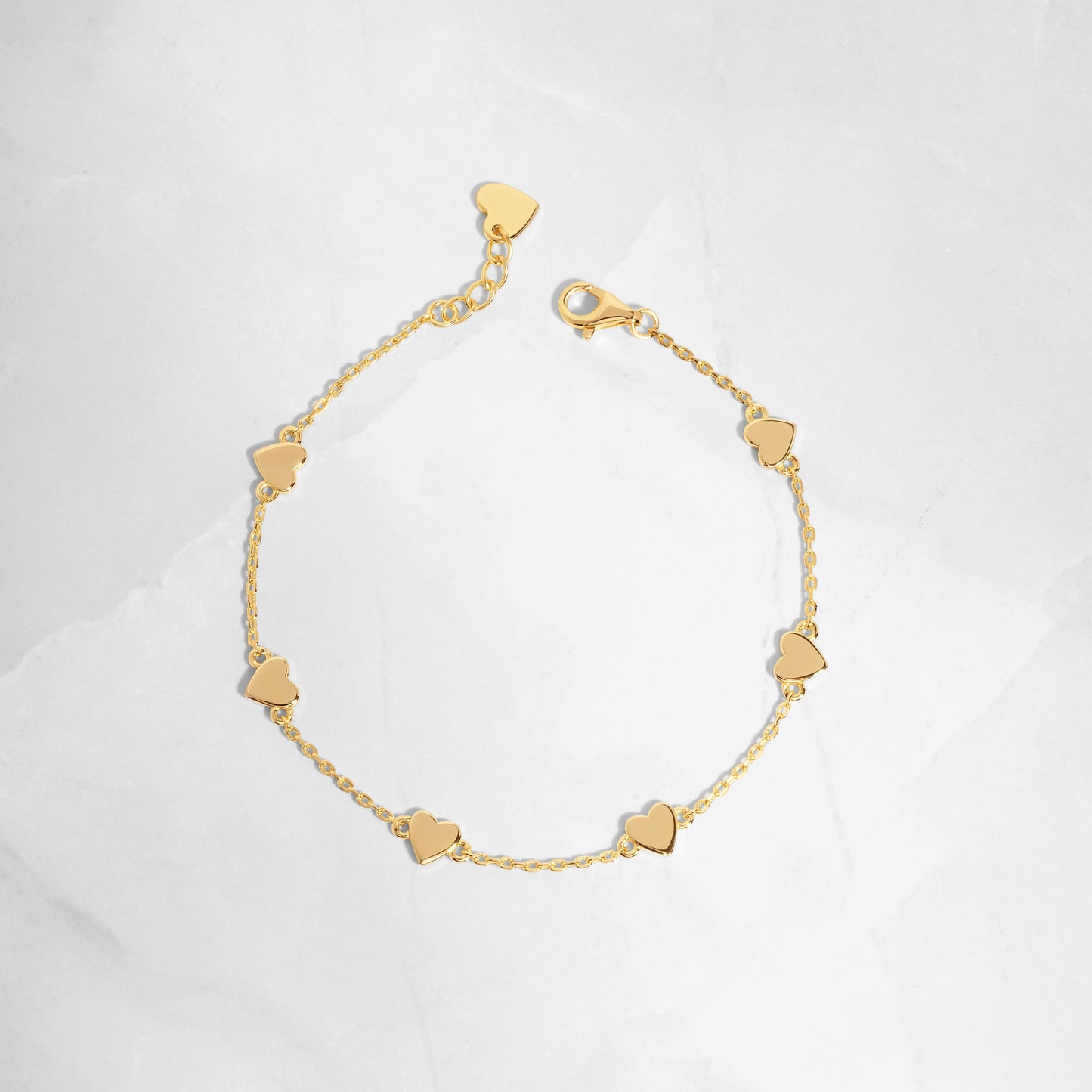 Flat-lay of the love bracelet, highlighting its delicate gold finish and heart charm details.