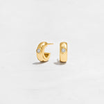 Closeup image of gold huggie hoops with diamond bezel design