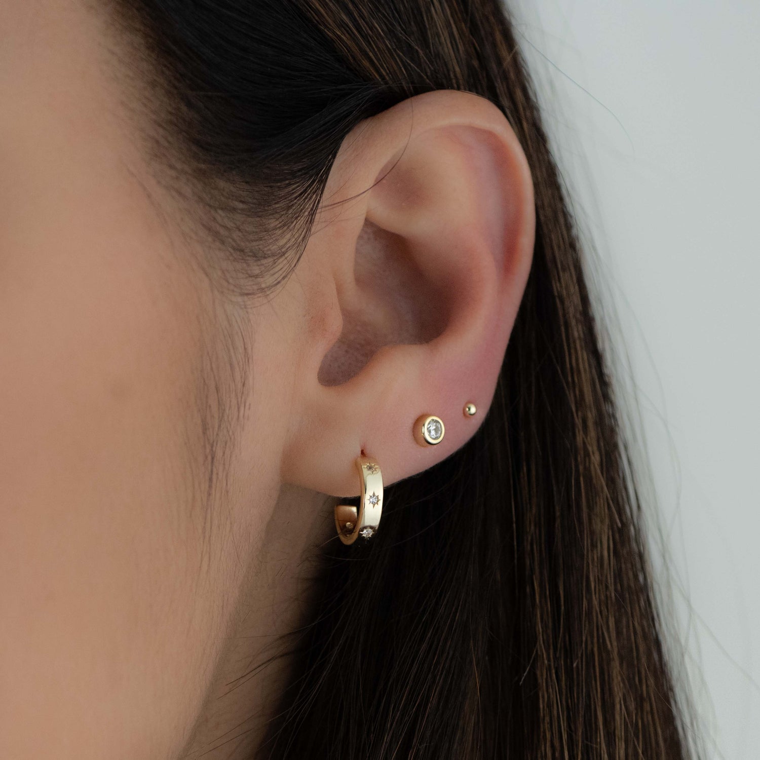 Gold hoop earrings with star studded design from Sami Jewels, showcasing the detailed celestial pattern on the earrings.