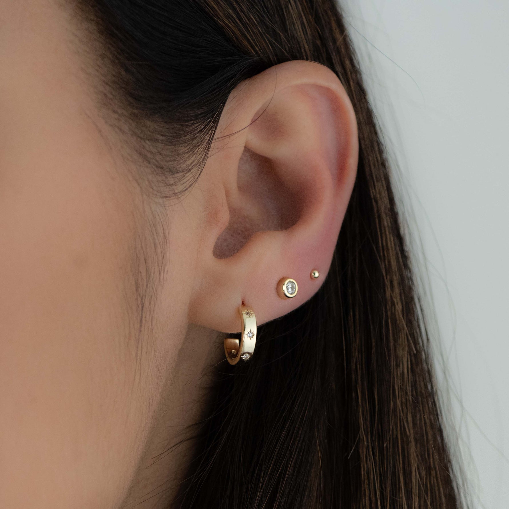 Gold hoop earrings with star studded design from Sami Jewels, showcasing the detailed celestial pattern on the earrings.