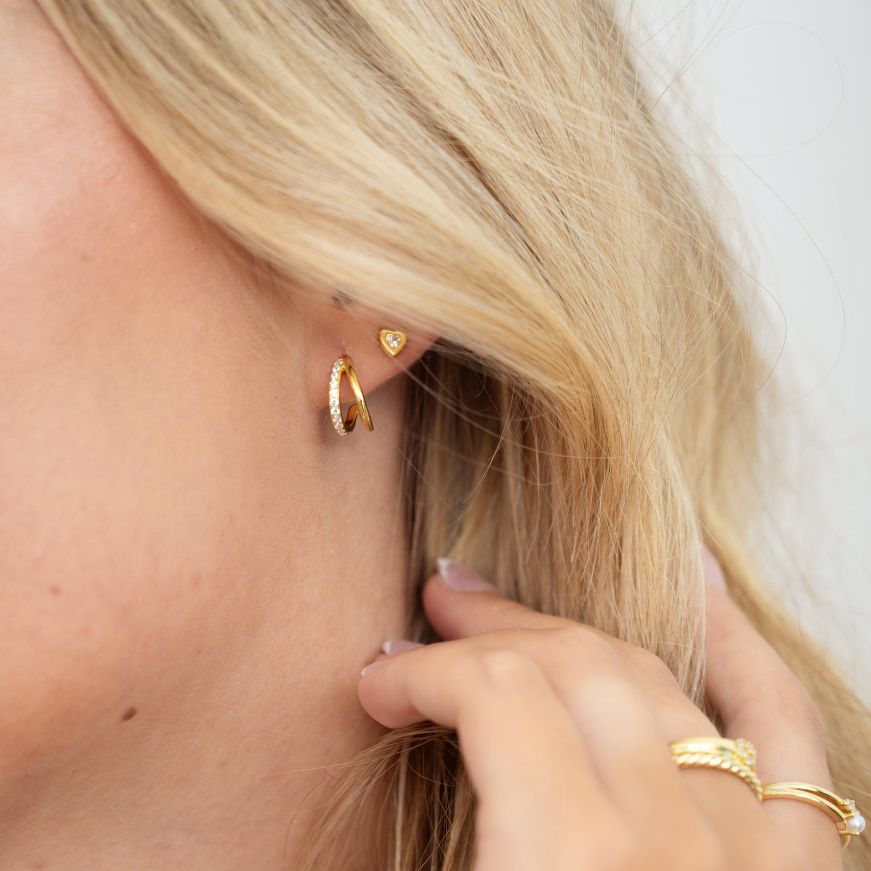 model wearing small hoop hoop earrings paired with a heart stud