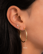 gold 32mm infinity hoop earrings on model