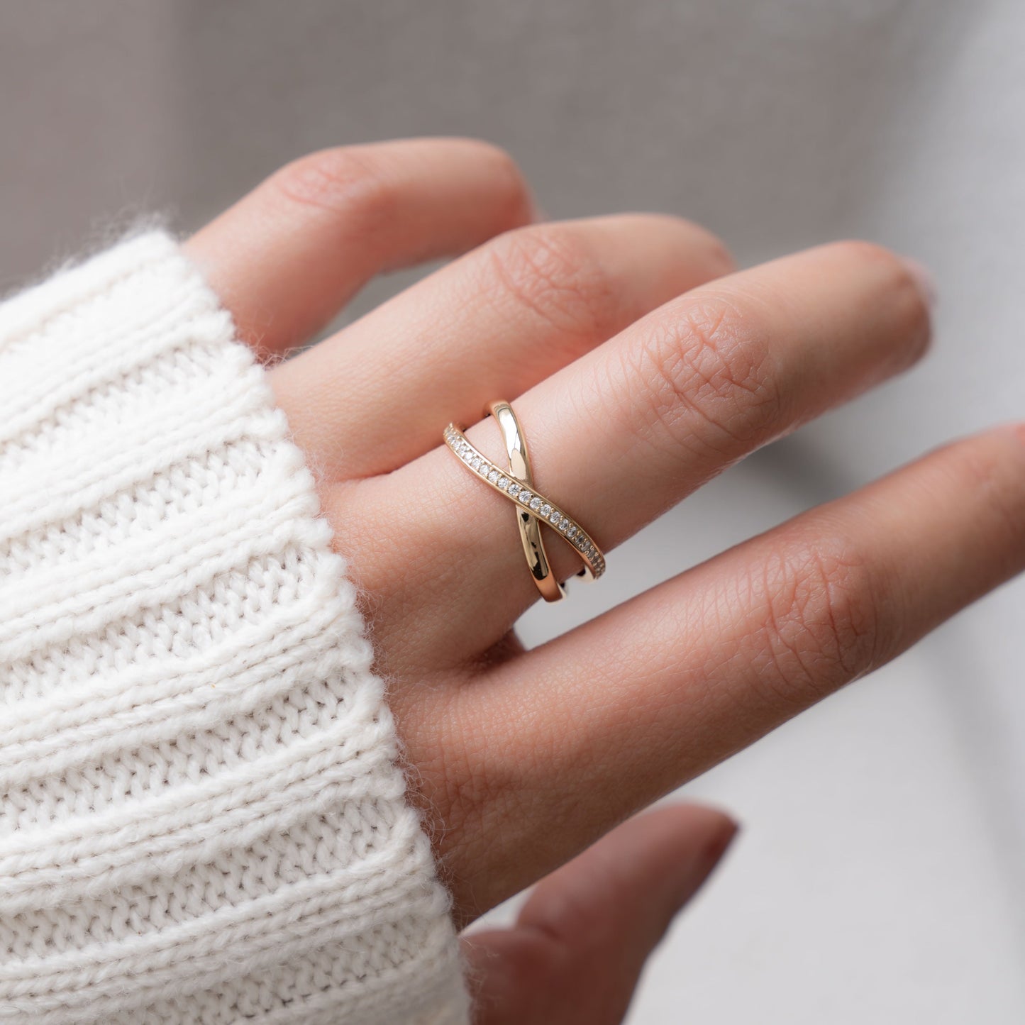 Close-up of a diamond X ring in silver, worn on the model’s finger.