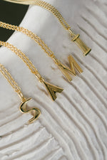 gold initial necklace spelling out "Sami" neutral background