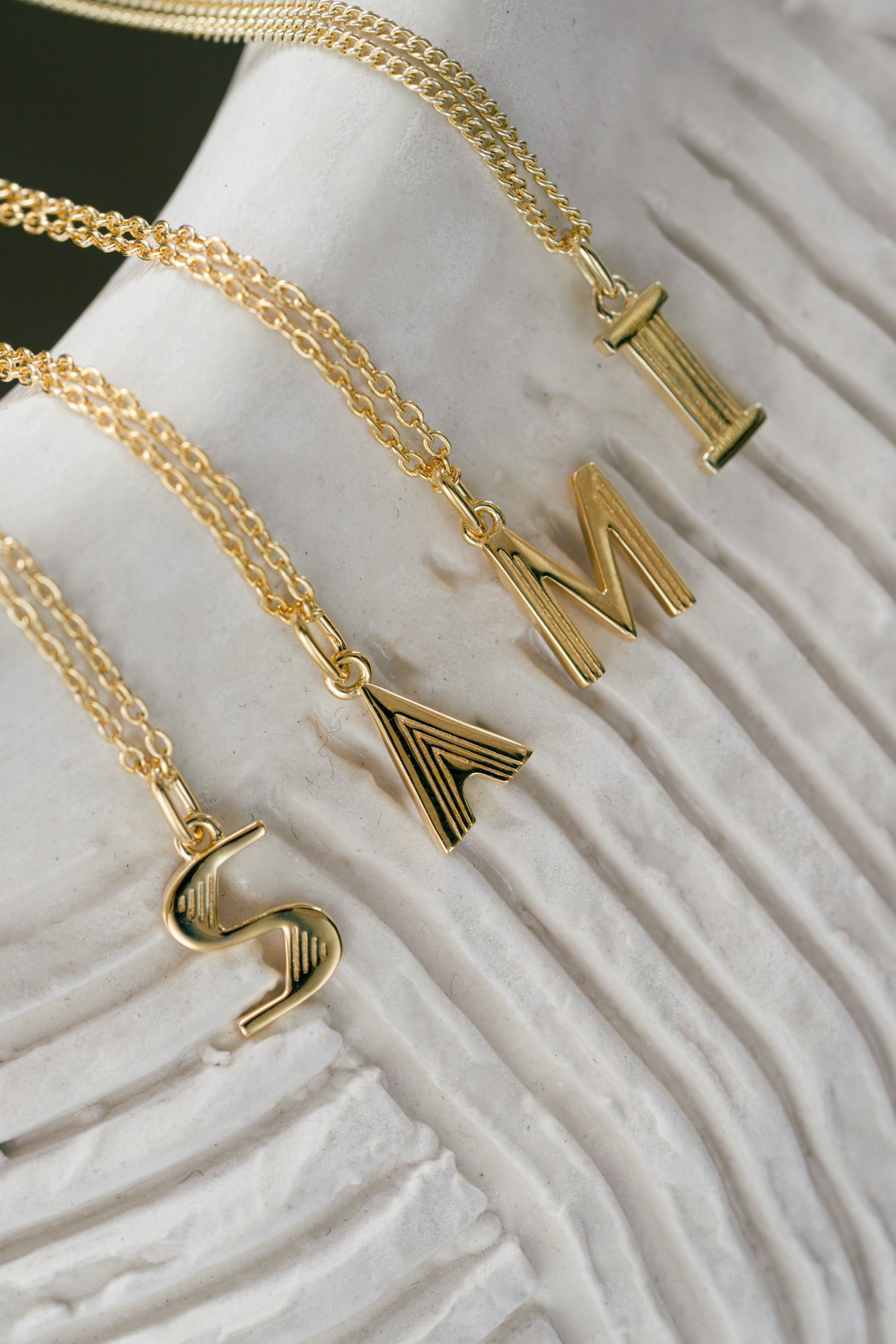gold initial necklace spelling out "Sami" neutral background