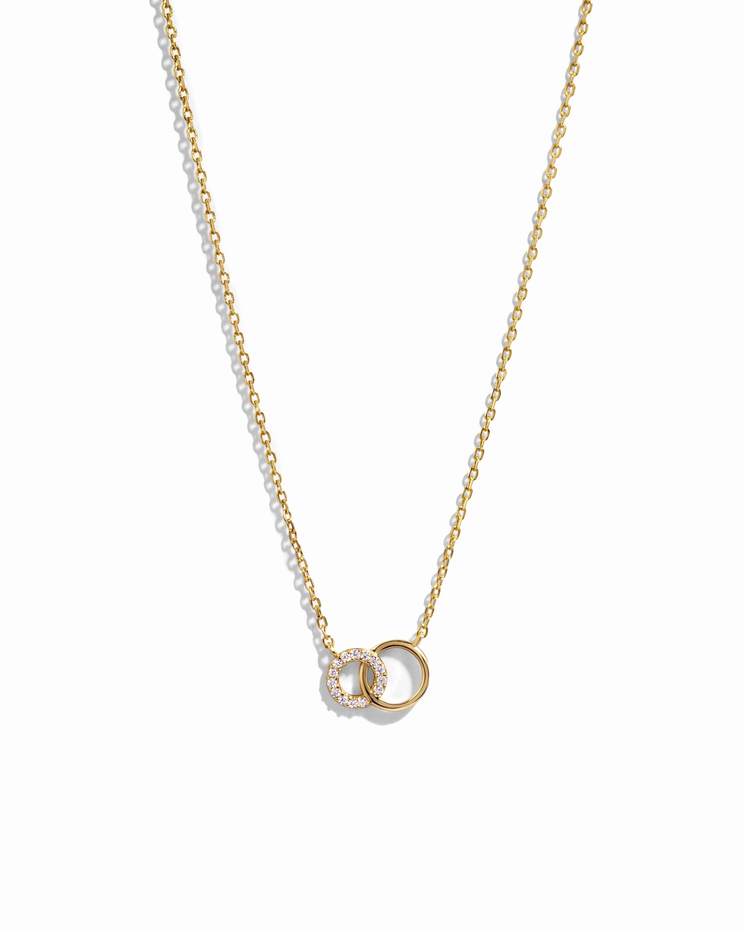 Gold interlocking circle necklace with a small pendant on a white background