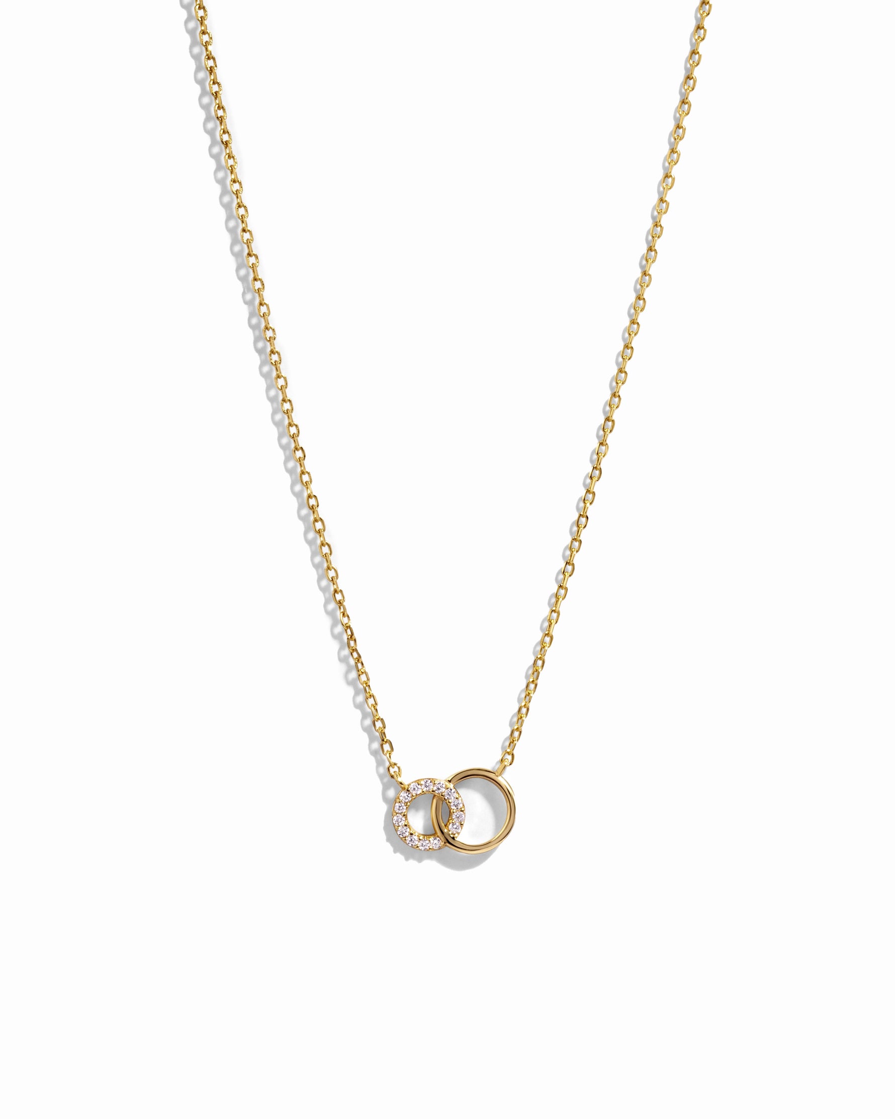 Gold interlocking circle necklace with a small pendant on a white background