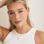 wearing wearing dainty gold necklaces paired with gold hoop earrings and diamond stud earrings