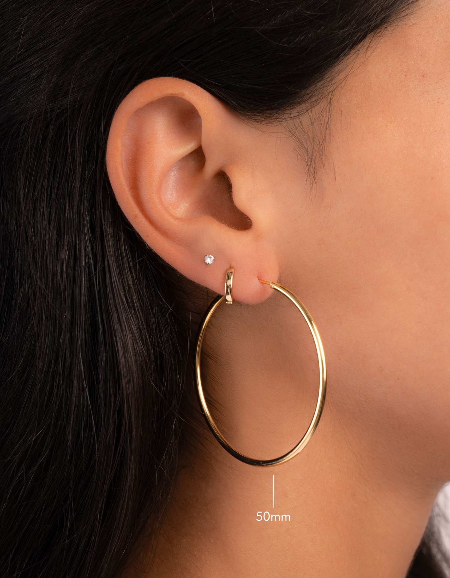 gold 50mm infinity hoop earrings on model