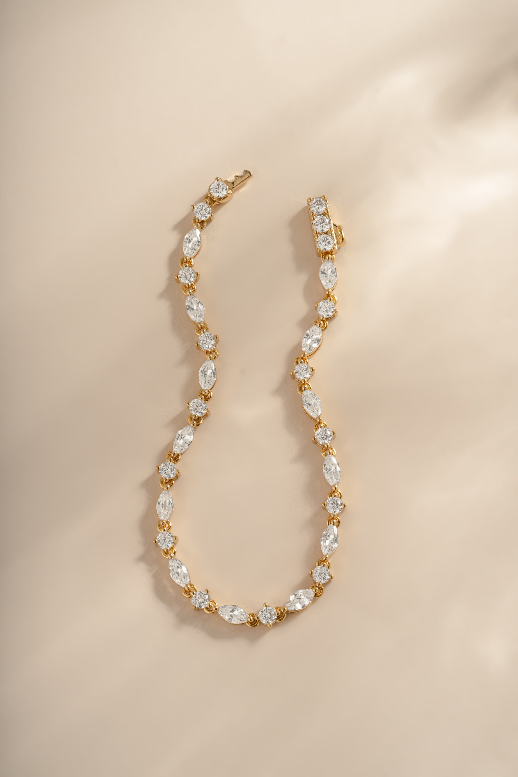 Gold Marquise and round stone diamond bracelet from Sami Jewels displayed in a flat lay.